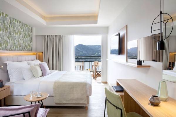 Innenansicht eines Schlafzimmers im Dolce Athens Attica Riviera Hotel mit Blick auf die Berge.