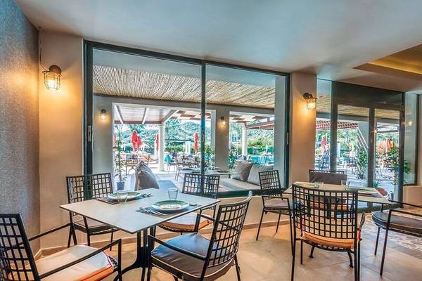 Innenansicht des Restaurants im Dolce Athens Attica Riviera Hotel mit Blick auf den Pool.