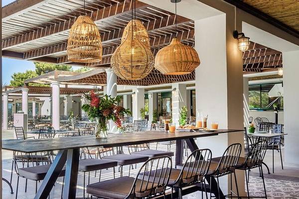 Außensitzplätze des Hotels Dolce Athens Attica Riviera mit Tischen und Stühlen.