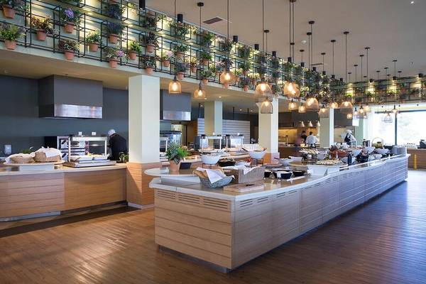 Buffettisch im Hotel Dolce Athens Attica Riviera mit verschiedenen Speisen, Blumenarrangements und Lampen.