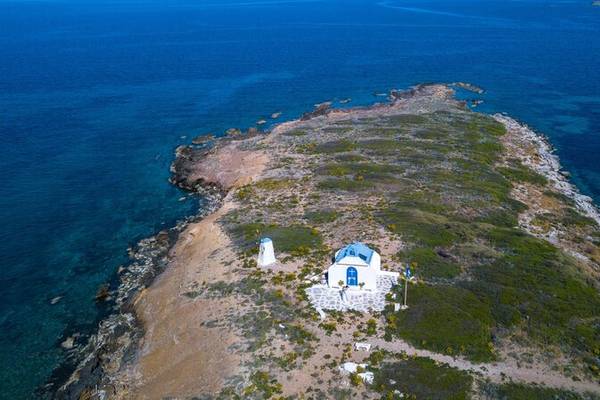 Luftaufnahme einer kleinen Insel mit einer Kirche und einem Leuchtturm am Rande.