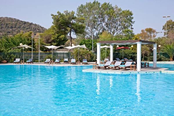 Pool-Bereich im Dolce Athens Attica Riviera Hotel mit Liegestühlen und Sonnenschirmen.