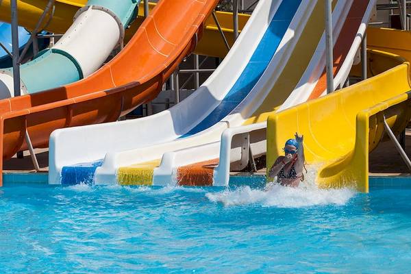 Ein Schwimmer kommt in einem Freibad mit bunten Wasserrutschen an, darunter der Sultan of Dreams.