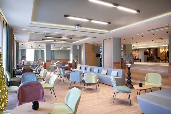 Hotellobby des Dolce Athens Attica Riviera mit bunten Stühlen, Tischen und Sofas.