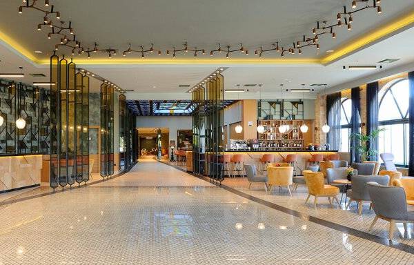 Foyer des Dolce Athens Attica Riviera Hotels mit moderner Architektur, Möbeln und Pflanzen.