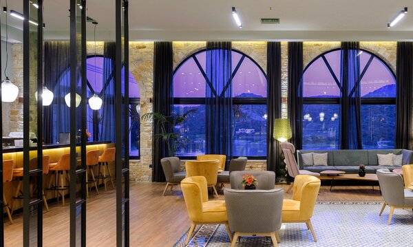 Hotel-Loungebereich des Dolce Athens Attica Riviera mit großen Fenstern und modernen Möbeln.