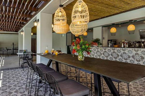 Frühstücksbereich des Dolce Athens Attica Riviera Hotels mit Tischen, Stühlen und Blumen.