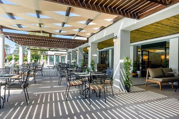 Terrasse des Dolce Athens Attica Riviera Hotels mit Tischen und Stühlen