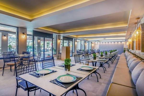 Innenbereich des Restaurants im Dolce Athens Attica Riviera Hotel mit gedeckten Tischen und Stühlen.