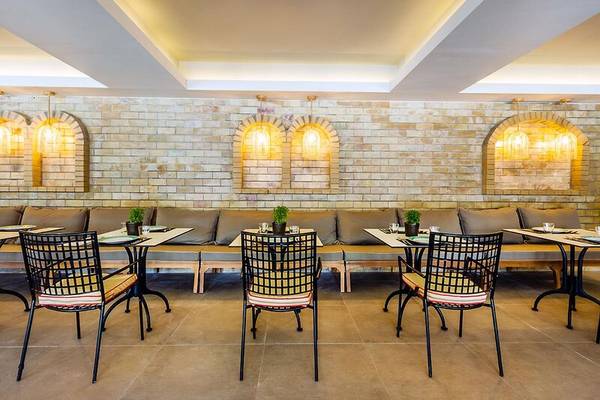 Innenbereich des Dolce Athens Attica Riviera Hotels mit Tischen und Stühlen.