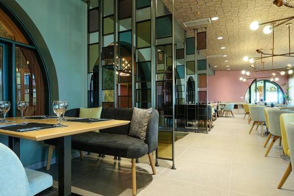 Innenbereich des Dolce Athens Attica Riviera Hotels mit Tischen, Stühlen und modernen Möbeln.