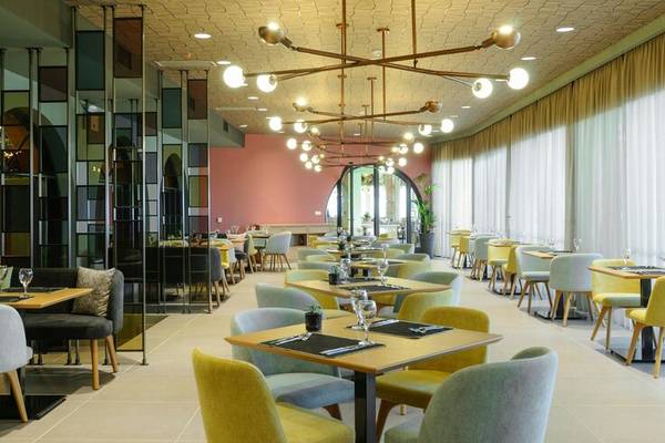 Innenbereich des Restaurants im Dolce Athens Attica Riviera Hotel mit farbenfrohen Stühlen und Tischen.