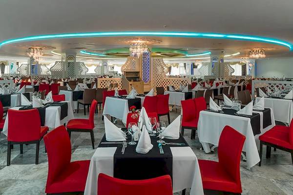 Innenansicht des Restaurants im Sultan of Dreams Hotel mit runden Tischen, roten Stühlen und blauen Beleuchtungselementen.