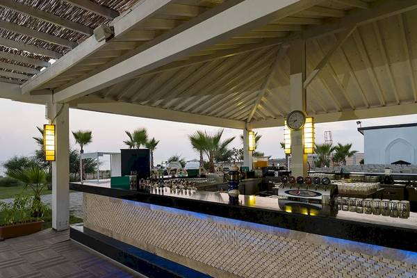 Terrassenbar des Sultan of Dreams Hotels mit Barkeeperstation und Palmen im Hintergrund.