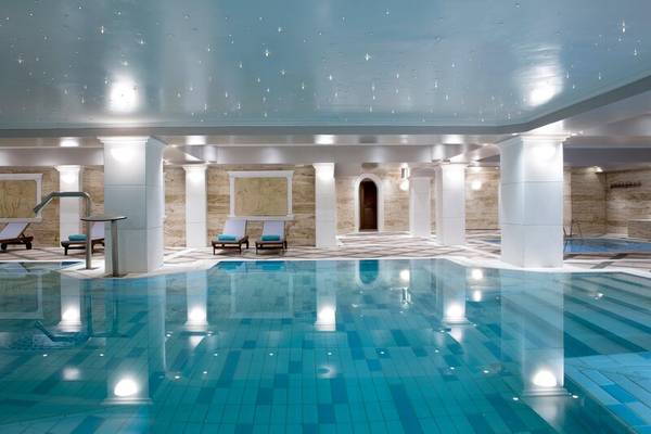Schwimmbecken im Hotel Dolce Athens Attica Riviera mit blauen Kacheln und weißen Säulen