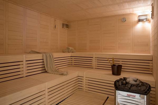 Innenansicht der Sauna im Dolce Athens Attica Riviera mit Holzbänken, Handtüchern und einem Harvia-Ofen.