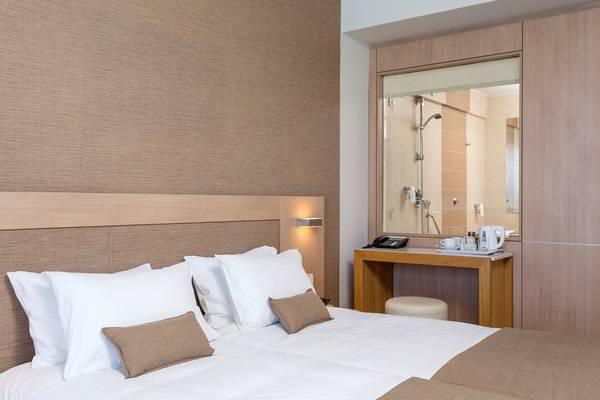 Schlafzimmer im I Resort Beach Hotel & Spa mit Doppelbett, weißen Kissen, Nachttisch und Spiegel