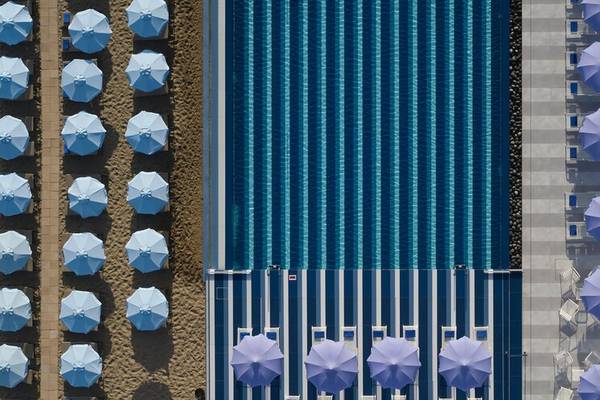 Luftaufnahme des Pools des I Resort Beach Hotel & Spa mit blauen Sonnenschirmen auf beiden Seiten.