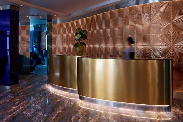 Empfangsbereich des I Resort Beach Hotel & Spa mit goldener Theke und gemusterten Wänden.