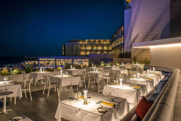 Außenbereich des I Resort Beach Hotel & Spa bei Nacht mit beleuchteten Tischen und Stühlen.