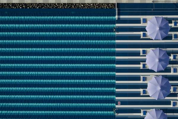 Oberansicht des Pools im I Resort Beach Hotel & Spa mit Sonnenschirmen und Liegen.