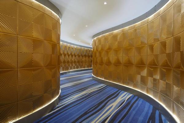 Innenbereich des I Resort Beach Hotel & Spa mit goldenen geometrischen Wandverkleidungen und blauem Streifenboden.