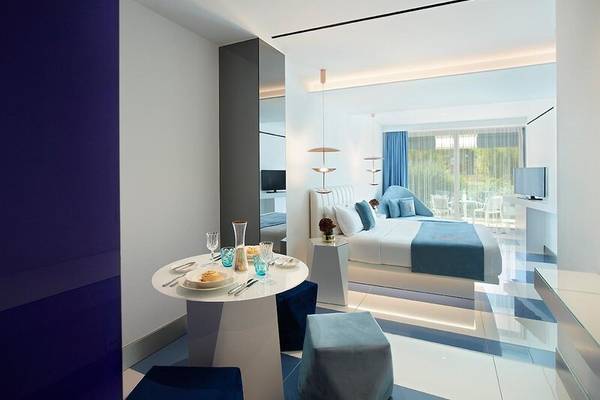 Interieur des I Resort Beach Hotel & Spa Zimmers mit Tisch, Betten und Ausblick auf den Garten