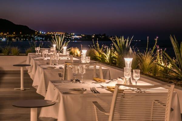 Außenterrasse des I Resort Beach Hotel & Spa bei Nacht mit illuminierten Tischen und Blick auf die Stadt