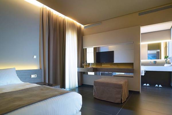 Innenansicht des Schlafzimmers im Nema Design Hotel & Spa mit einem Bett, Fernseher und einem Spiegelschrank.