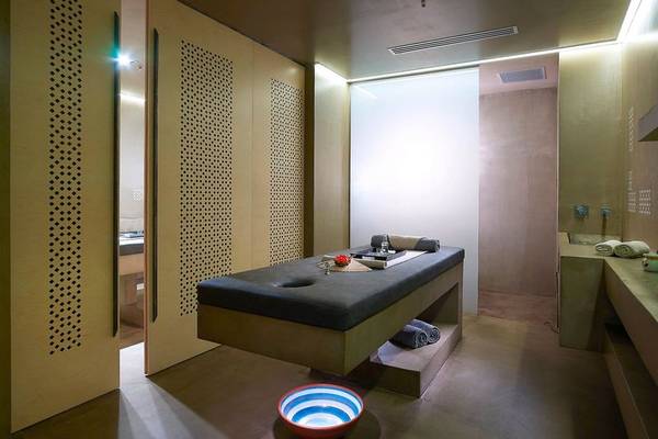 Massageraum im Nema Design Hotel & Spa mit einem Massagetisch, einem roten und blauen Blumentopf und Perforationen an den Wänden.