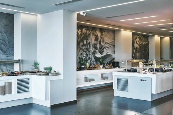 Innenbereich des Restaurants im Nema Design Hotel & Spa mit weißen Wänden, schwarzen Bodenfliesen und großen Wandgemälden.