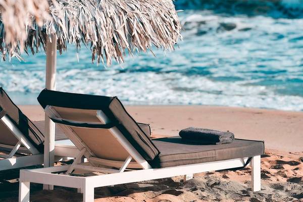 Strandliegen des Nema Design Hotel & Spa unter einem Sonnenhut am Strand