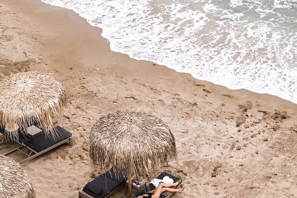 Personen liegen auf Sonnenliegen am Strand des Nema Design Hotels & Spa.