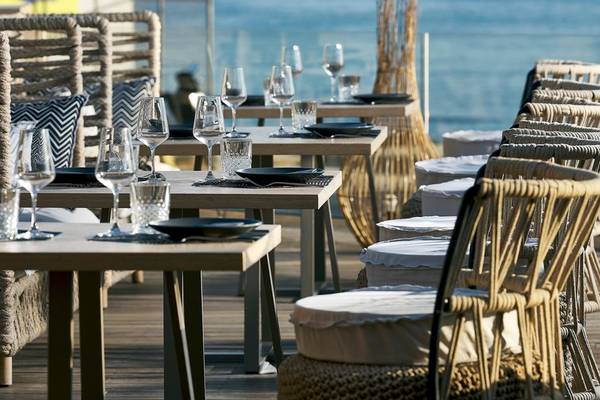Terrasse des Nema Design Hotels & Spa mit Tischen und Stühlen am Meer