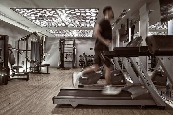 Fitnessbereich im Nema Design Hotel mit einem Mann, der auf einem Laufband läuft.