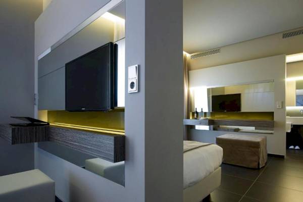 Innenansicht eines Zimmers im Nema Design Hotel mit moderner Einrichtung, Fernseher und Bett.