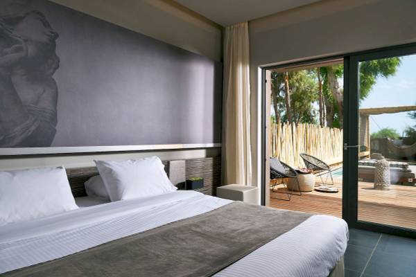 Schlafzimmer im Nema Design Hotel & Spa mit großem Bett, weißen Kissen und Panoramafenster zum Pool.