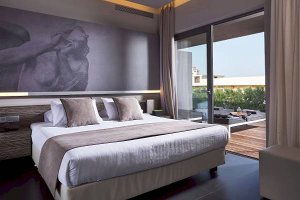 Schlafzimmer im Nema Design Hotel mit großer Wandkunst, bequemem Bett und Terrassenaussicht.