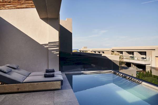 Außenbereich des Nema Design Hotel & Spa mit Blick auf den Pool und Liegestühlen.