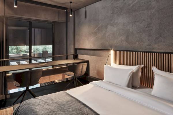 Schlafzimmer im Nema Design Hotel & Spa mit Bett, Schreibtisch und Stühlen.