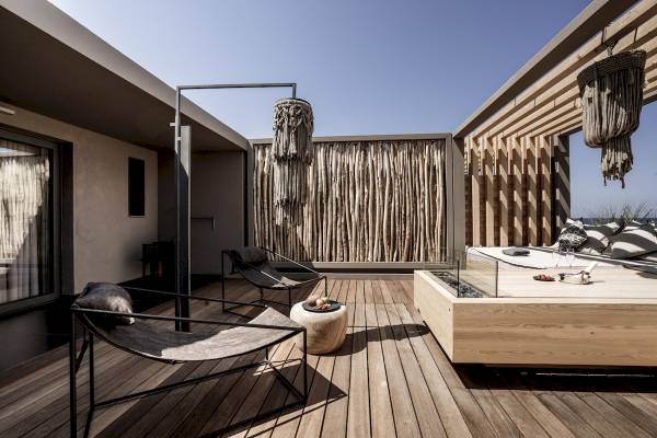 Terrasse des Nema Design Hotel & Spa mit Lounge-Sesseln, Holzdeck und Aussicht auf das Meer.
