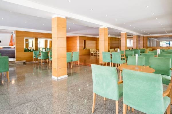 Innenbereich des Restaurants im La Santa Maria Playa Hotel mit grünen Stühlen und Holztischen.