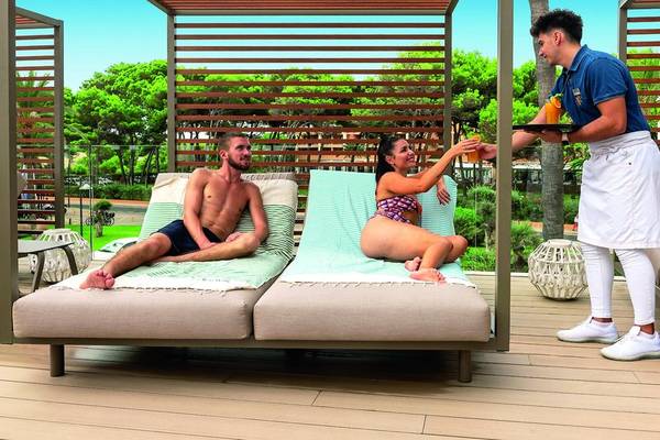 Gäste auf der Terrasse des Allsun Hotel Sumba, ein Kellner serviert Getränke.