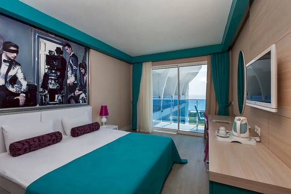 Hotelzimmer des Sultan of Dreams mit Meerblick, großes Bett, Wandbild, und offener Terrasse.