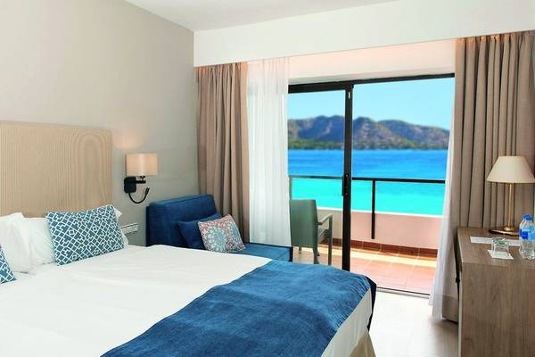 Hotelzimmer mit Meerblick im Allsun Hotel Sumba mit einem Bett, Sofa und Schreibtisch.