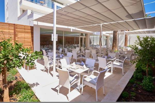 Außenterrasse des Girasol Hotels mit weißen Tischen und Stühlen unter einem Sonnensegel.