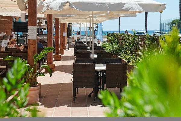 Terrasse des Girasol Hotels mit Tischen, Stühlen und Sonnenschirmen am Meer