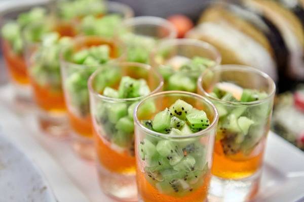 Mehrere Gläser mit gekieselten Kiwi-Cocktails auf einem weißen Tablett.