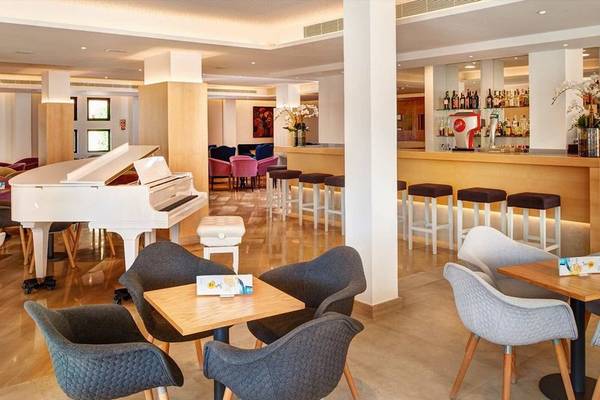 Lounge-Bereich im Girasol Hotel mit einem weißen Klavier und einer Bar.