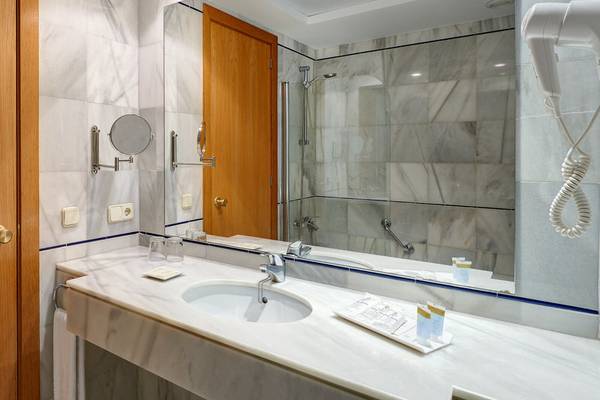 Gesamtansicht des Badezimmers im Girasol Hotel mit Spiegel und Dusche.